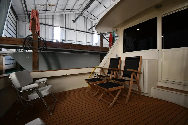 Stormy Yacht Photos Pics 1988 Viking 48 Convertible yacht interior with wooden deck and folding chairs in a boat shed.