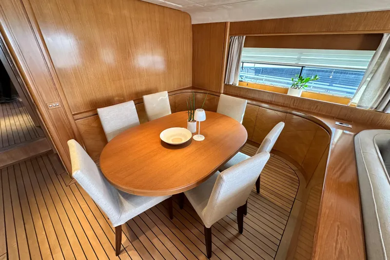 Galini Yacht Photos Pics Elegant dining area on 2001 Cantieri di Pisa 27s yacht with wooden table and chairs.