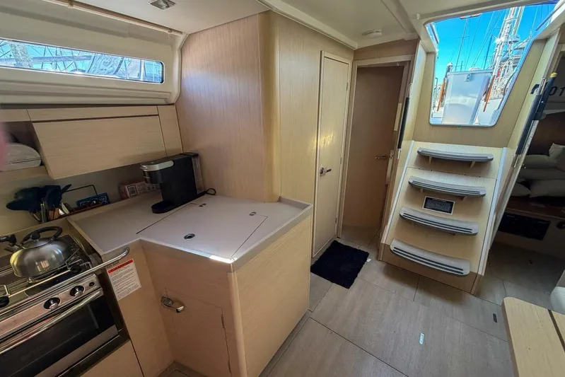 Happy Ours Yacht Photos Pics Interior of 2022 Beneteau Oceanis 40.1 yacht, featuring modern kitchen and wooden stairs.