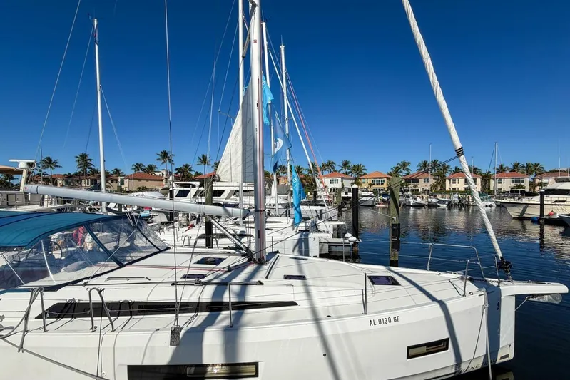 Happy Ours Yacht Photos Pics 2022 Beneteau Oceanis 40.1 sailboat docked in a sunny marina with palm trees.