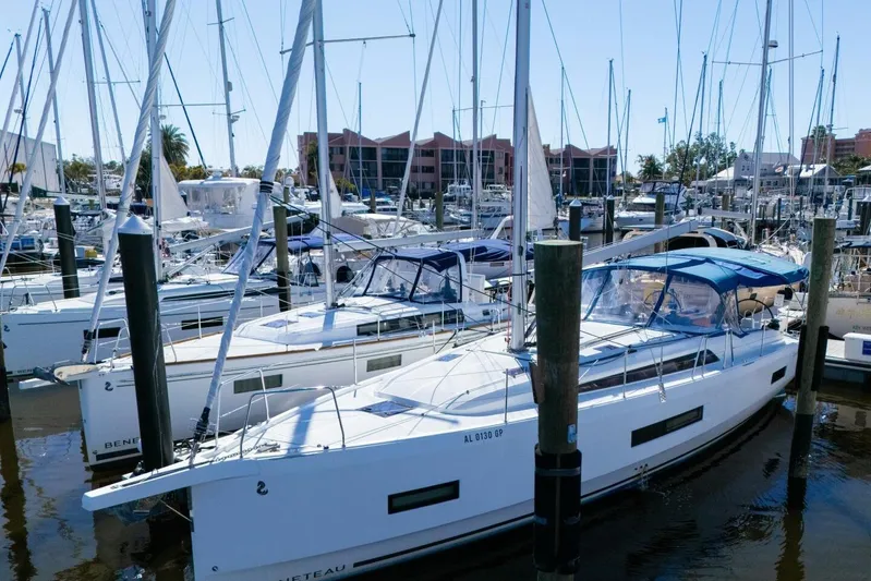 Happy Ours Yacht Photos Pics 2022 Beneteau Oceanis 40.1 sailboat docked in a marina, surrounded by other boats.