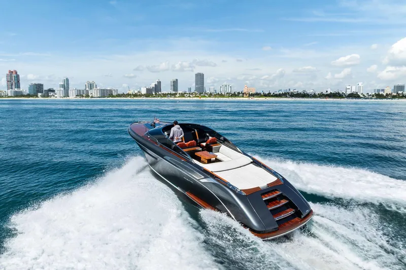 Grey Yacht Photos Pics 2023 Riva Rivamare luxury yacht cruising near a city skyline on a sunny day.