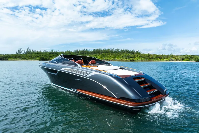 Grey Yacht Photos Pics 2023 Riva Rivamare luxury yacht cruising on a serene lake under a blue sky.