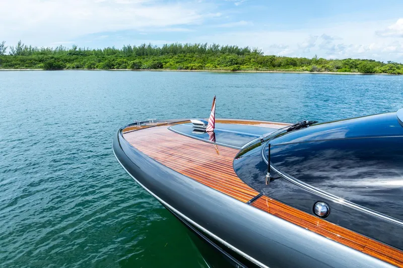 Grey Yacht Photos Pics 2023 Riva Rivamare yacht on serene water with lush green shoreline.