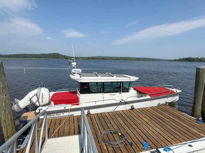 Willow Run Yacht Photos Pics 2021 Axopar 28 CABIN boat docked by a wooden pier on a sunny day.