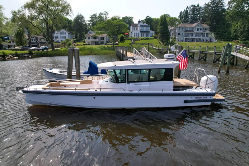 Willow Run Yacht Photos Pics 2021 Axopar 28 CABIN boat docked by waterfront homes, displaying an American flag.