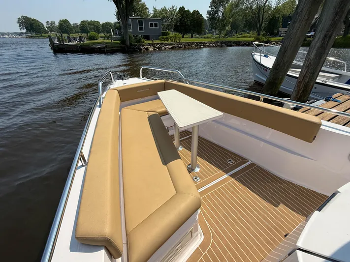 Willow Run Yacht Photos Pics 2021 Axopar 28 CABIN boat with tan seating and table, docked by a scenic shoreline.