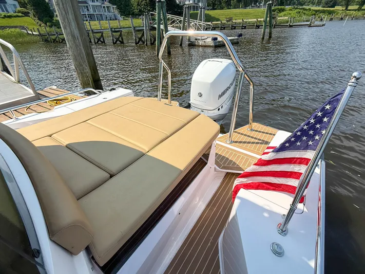 Willow Run Yacht Photos Pics 2021 Axopar 28 CABIN boat with American flag, docked by a scenic waterfront.