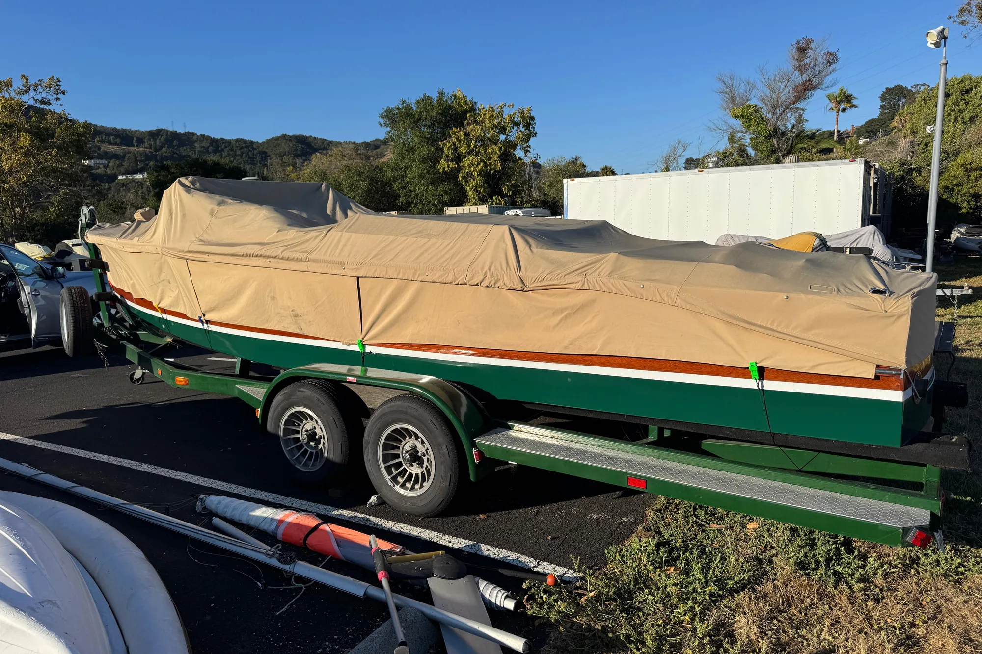 1987 Grand Craft Triple Cockpit Runabout covered on trailer, parked outdoors.