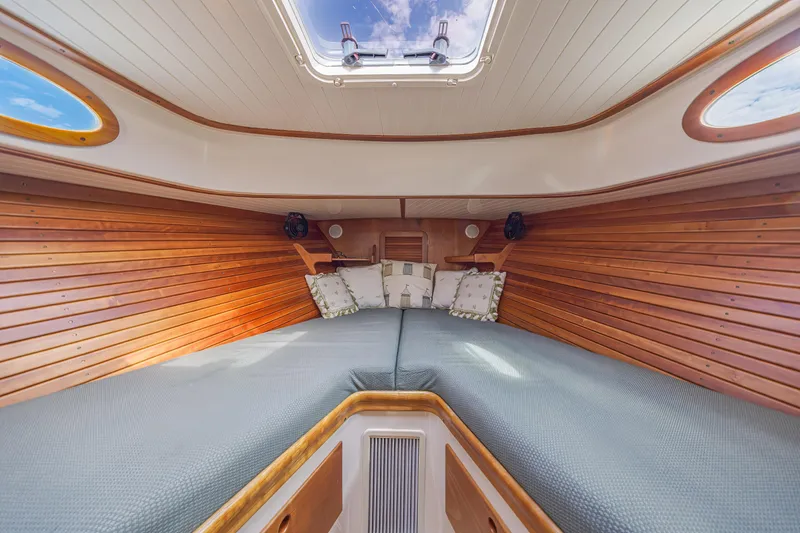 Genie Yacht Photos Pics 1999 Hinckley Picnic Boat interior with wooden paneling and cozy bedding.