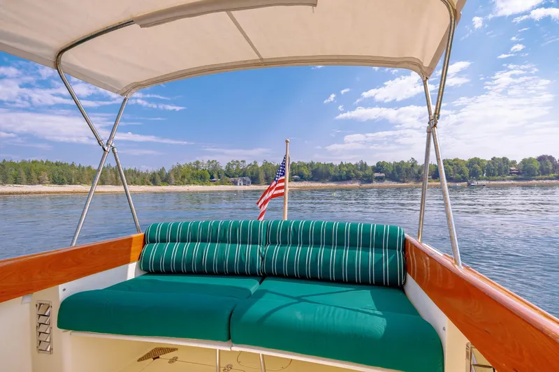 Genie Yacht Photos Pics 1999 Hinckley Picnic Boat with canopy, green seating, and American flag on calm water.
