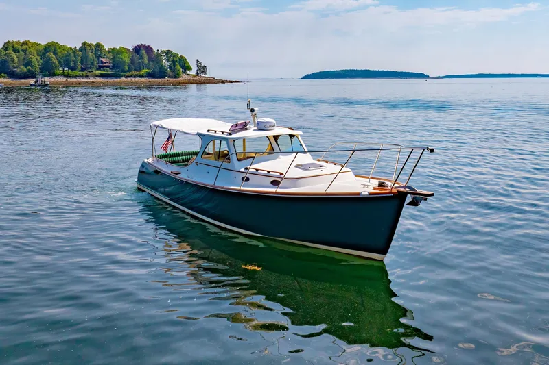 Genie Yacht Photos Pics 1999 Hinckley Picnic Boat cruising on calm waters near a scenic shoreline.