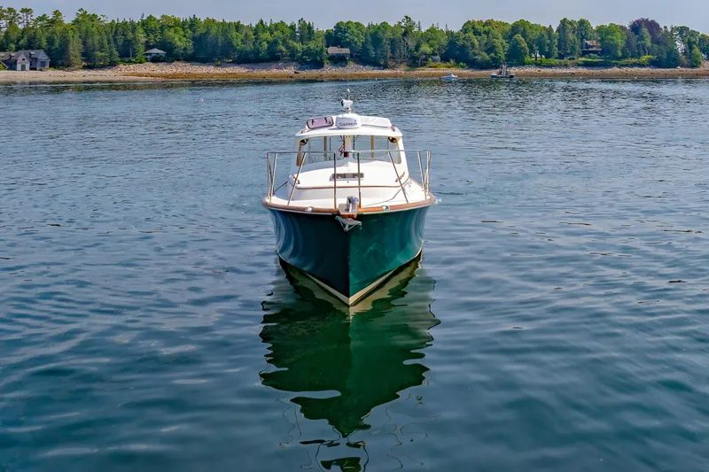 Genie Yacht Photos Pics 1999 Hinckley Picnic Boat on calm water with scenic shoreline background.