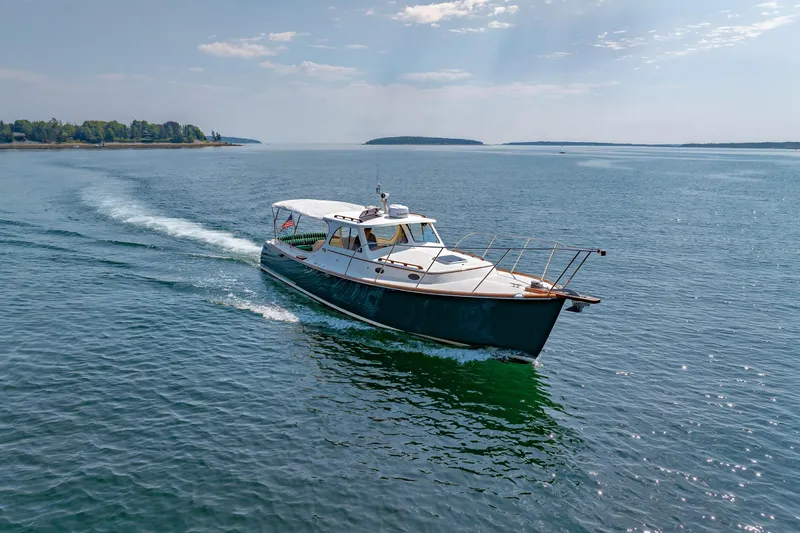 Genie Yacht Photos Pics 1999 Hinckley Picnic Boat cruising on a serene lake under a clear sky.