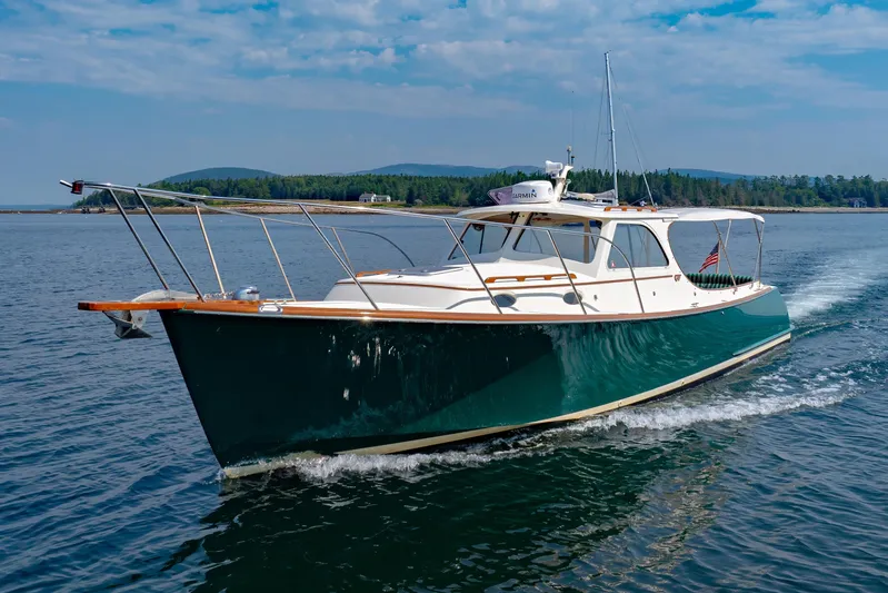 Genie Yacht Photos Pics 1999 Hinckley Picnic Boat cruising on a serene lake with scenic forested background.