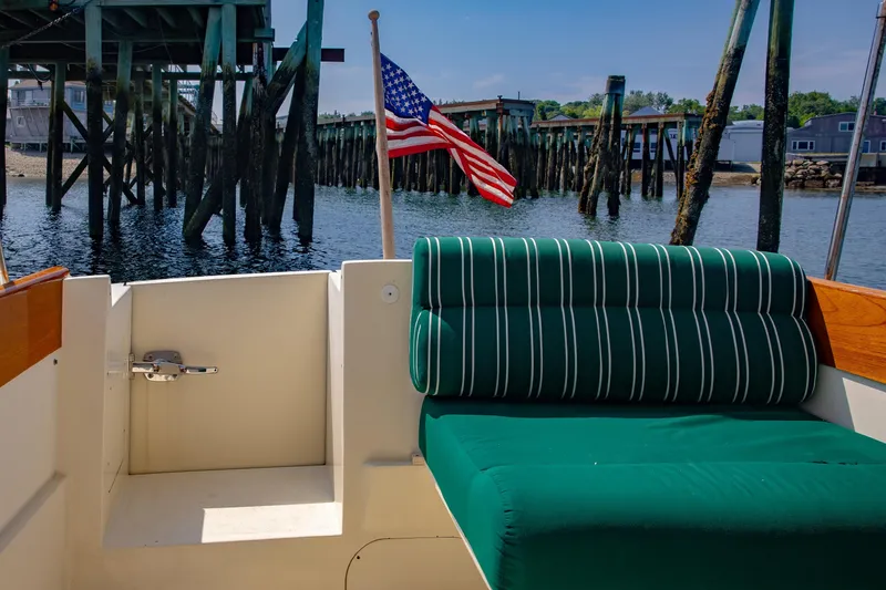 Genie Yacht Photos Pics 1999 Hinckley Picnic Boat interior with green striped seating, American flag, and dock view.