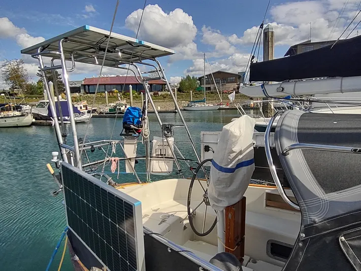 Wu Wei Yacht Photos Pics 1997 Pacific Seacraft 37 sailboat docked in a marina, featuring solar panels and a covered helm.
