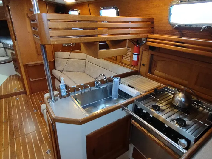 Wu Wei Yacht Photos Pics Interior of 1997 Pacific Seacraft 37 sailboat with wooden cabinetry and compact kitchen.