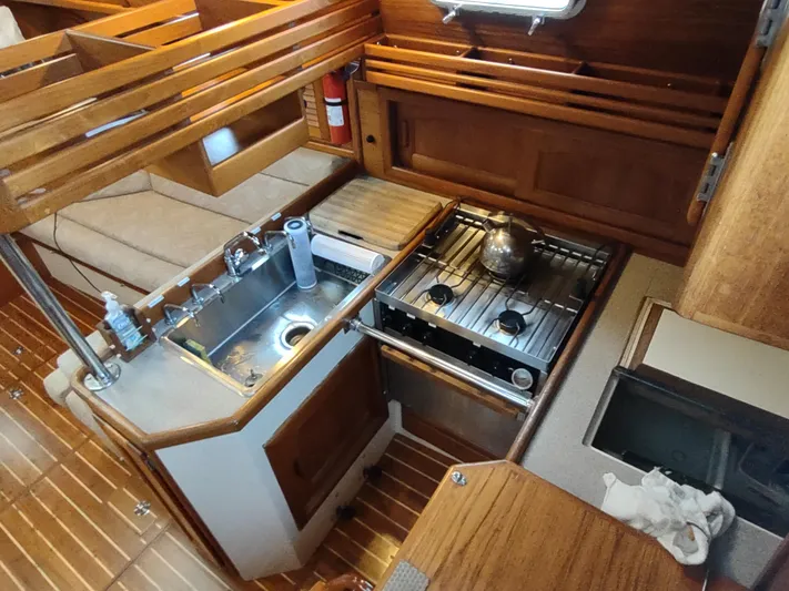 Wu Wei Yacht Photos Pics 1997 Pacific Seacraft 37 yacht interior kitchen with stove, sink, and wooden cabinetry.