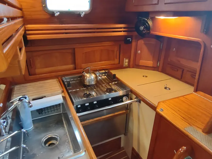 Wu Wei Yacht Photos Pics Cozy 1997 Pacific Seacraft 37 yacht kitchen with stove, sink, and wooden cabinetry.