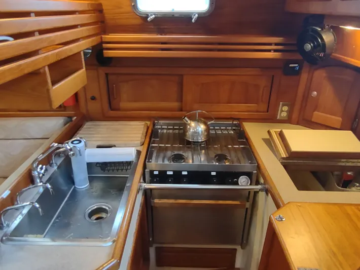 Wu Wei Yacht Photos Pics Galley of 1997 Pacific Seacraft 37 sailboat with stove, sink, and wooden cabinetry.