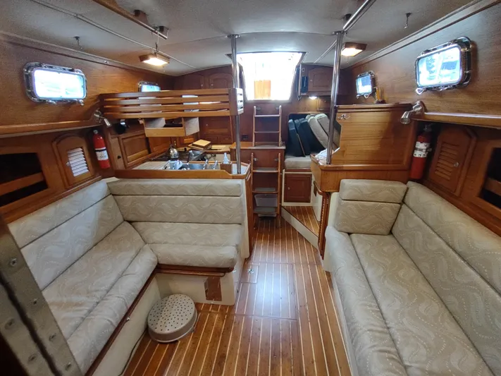 Wu Wei Yacht Photos Pics Interior of 1997 Pacific Seacraft 37 sailboat with wooden finish and cushioned seating.