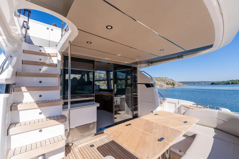 Whiskey Yacht Photos Pics Luxurious 2021 Princess F55 yacht deck with seating, table, and scenic water view.
