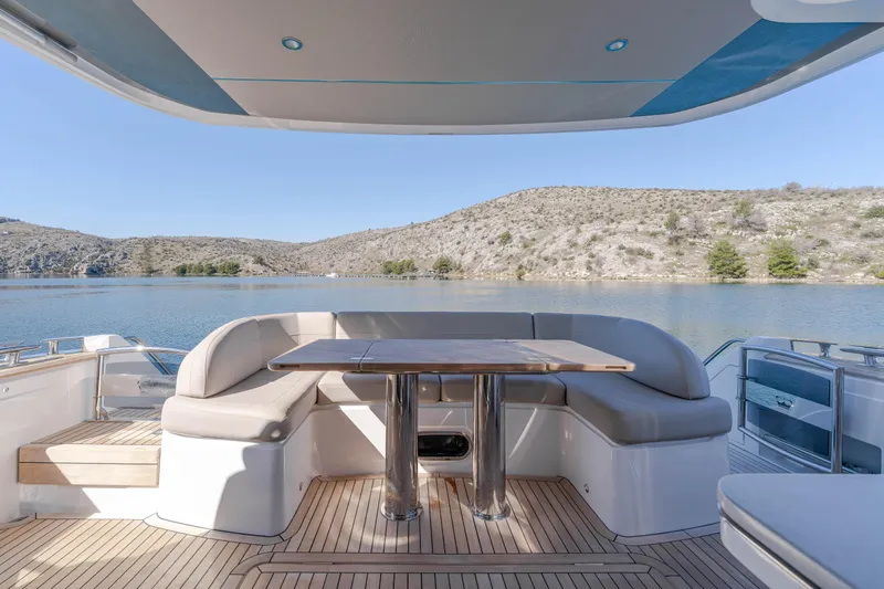 Whiskey Yacht Photos Pics Luxurious 2021 Princess F55 yacht deck with seating, table, and scenic water view.