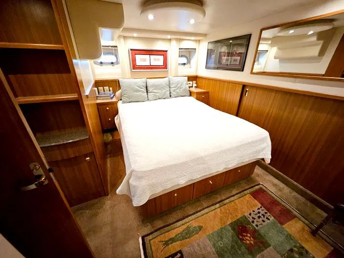  Yacht Photos Pics Luxurious bedroom interior of 2000 Bayliner 5288 Pilot House Motoryacht with cozy bed and wood paneling.