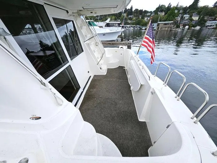  Yacht Photos Pics Bayliner 5288 Pilot House Motoryacht 2000, spacious deck with American flag, docked by waterfront.