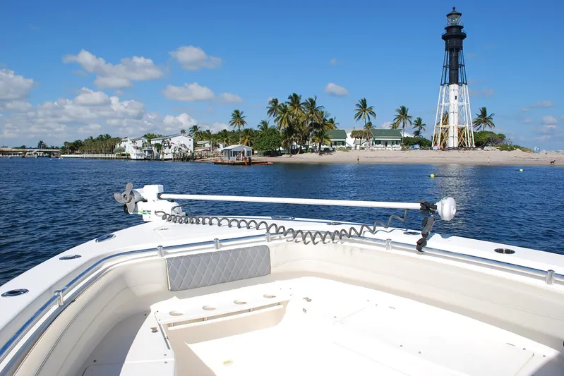 Playin Hooky Yacht Photos Pics 2019 Cobia 344 Center Console boat near lighthouse and palm trees on a sunny day.