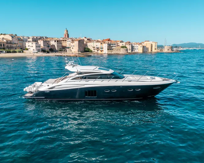  Yacht Photos Pics Luxurious 2011 Princess V62 yacht cruising near a coastal town under clear blue skies.