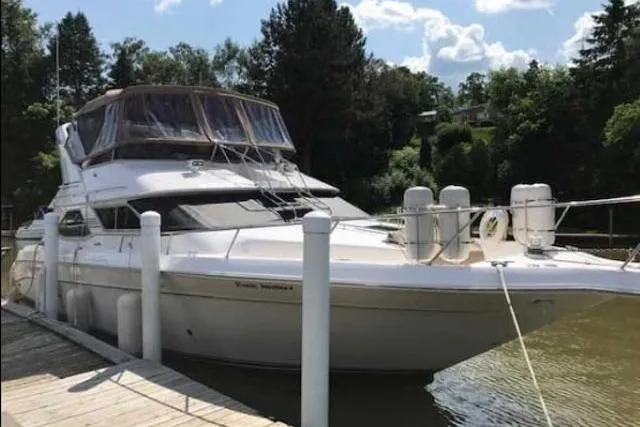 Basic Instinct Yacht Photos Pics 1995 Sea Ray 440 Express Bridge yacht docked by a scenic waterfront.