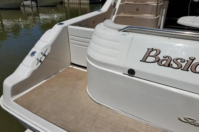 Basic Instinct Yacht Photos Pics 1995 Sea Ray 440 Express Bridge boat deck with "Basic" lettering, docked on calm water.