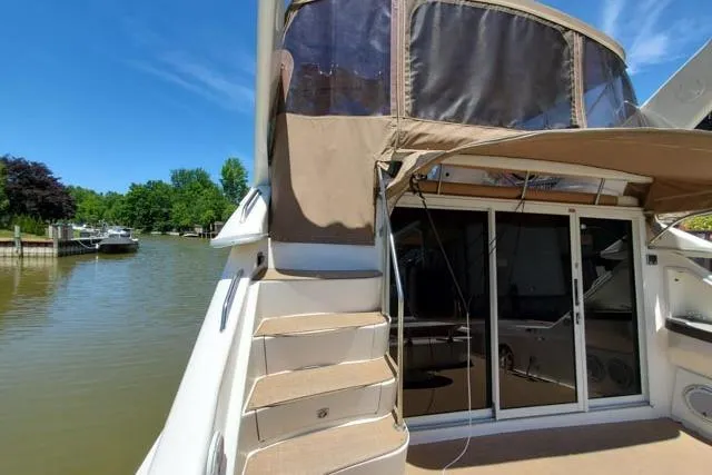 Basic Instinct Yacht Photos Pics 1995 Sea Ray 440 Express Bridge yacht docked by a serene river.
