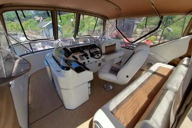 Basic Instinct Yacht Photos Pics 1995 Sea Ray 440 Express Bridge helm with white seating and panoramic windows.