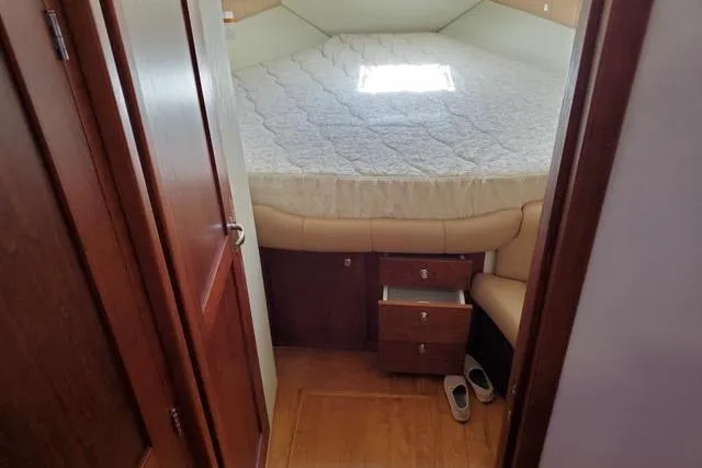 Basic Instinct Yacht Photos Pics 1995 Sea Ray 440 Express Bridge cabin with bed, wooden flooring, and storage drawers.