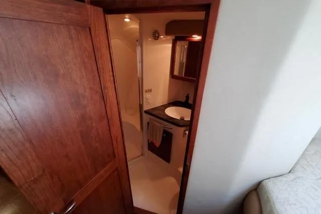 Basic Instinct Yacht Photos Pics 1995 Sea Ray 440 Express Bridge bathroom with wooden door, sink, and mirror.