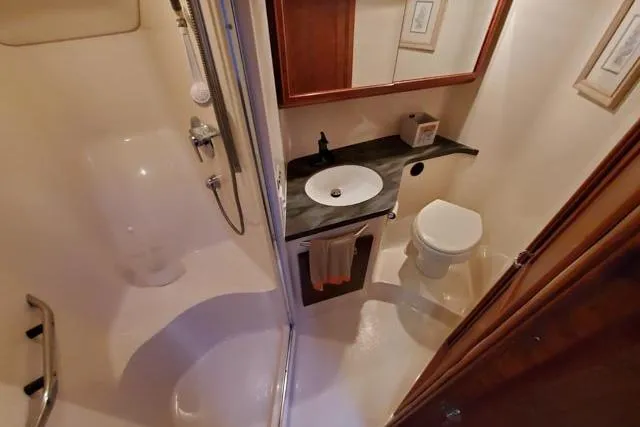 Basic Instinct Yacht Photos Pics Bathroom interior of 1995 Sea Ray 440 Express Bridge yacht, featuring shower, sink, and toilet.