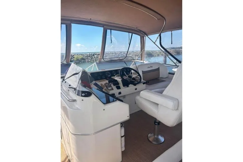 Basic Instinct Yacht Photos Pics 1995 Sea Ray 440 Express Bridge helm with white seating and panoramic windows.