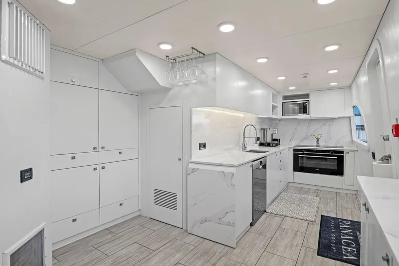 Panacea Yacht Photos Pics Modern kitchen interior on 2011 Mengi Yay 115 MY yacht, featuring sleek white cabinetry and appliances.