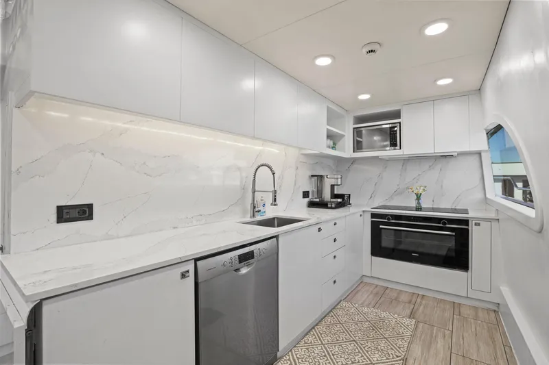 Panacea Yacht Photos Pics Modern yacht kitchen with sleek white cabinetry, marble backsplash, and stainless steel appliances on Mengi Yay 115 MY.