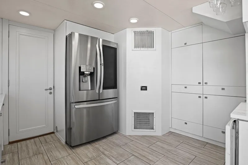 Panacea Yacht Photos Pics Modern kitchen with stainless steel refrigerator, white cabinetry, and tiled flooring on Mengi Yay 115 MY yacht.