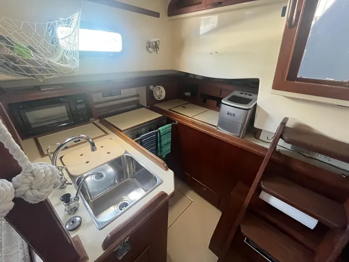  Yacht Photos Pics 1997 Island Packet 350 yacht kitchen with sink, wooden cabinetry, and appliances.