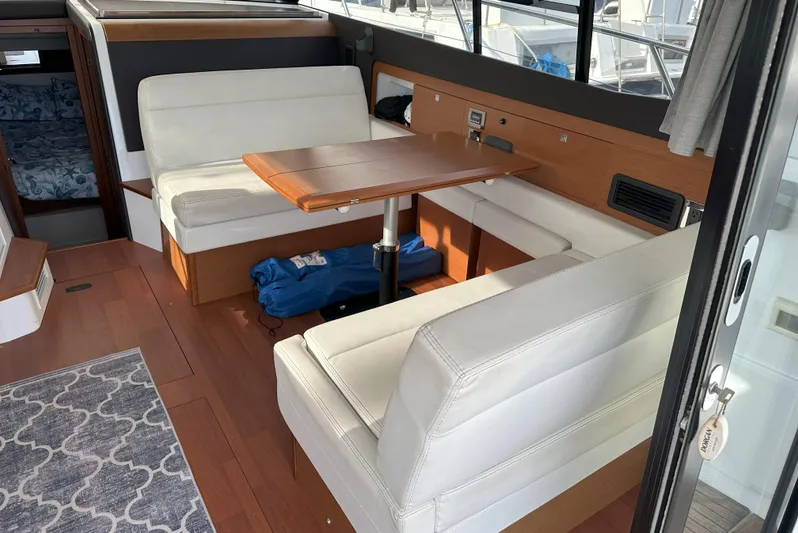 Tea Moana Yacht Photos Pics Interior of 2016 Jeanneau NC 11 boat with white seating and wooden table.