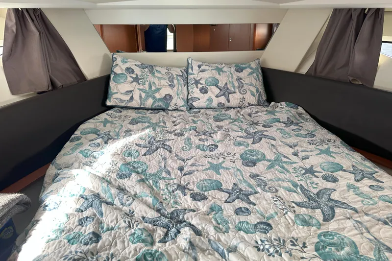 Tea Moana Yacht Photos Pics Cozy cabin interior of 2016 Jeanneau NC 11 with nautical-themed bedding.