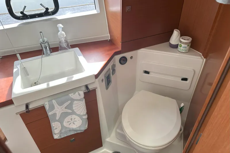 Tea Moana Yacht Photos Pics 2016 Jeanneau NC 11 boat bathroom with sink, toilet, and wooden cabinetry.