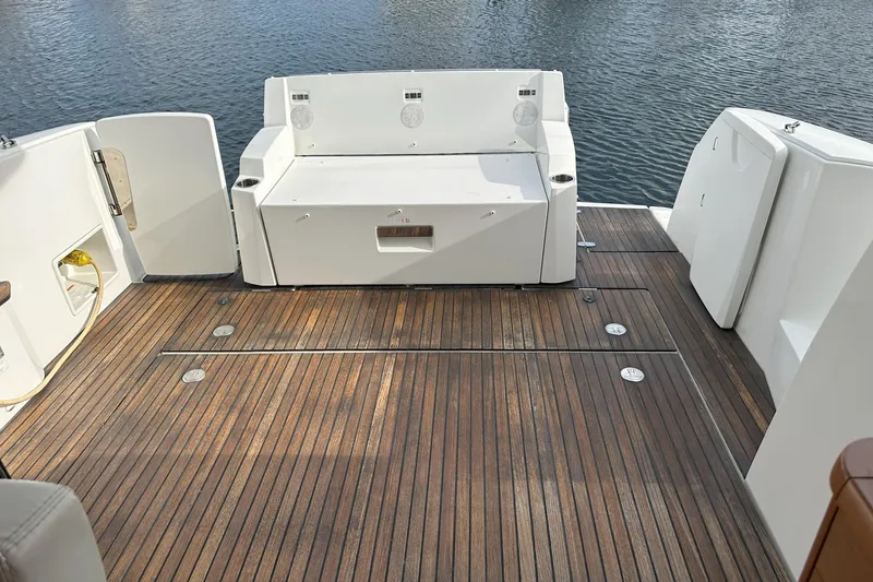 Tea Moana Yacht Photos Pics 2016 Jeanneau NC 11 boat deck with wooden flooring and white seating, overlooking water.