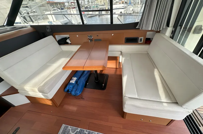 Tea Moana Yacht Photos Pics Interior of 2016 Jeanneau NC 11 with white seating and wooden table.