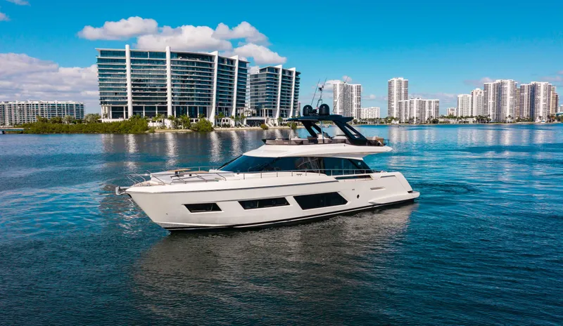 Our Trade Yacht Photos Pics 2022 Ferretti Yachts 670 cruising near modern waterfront buildings under a clear blue sky.